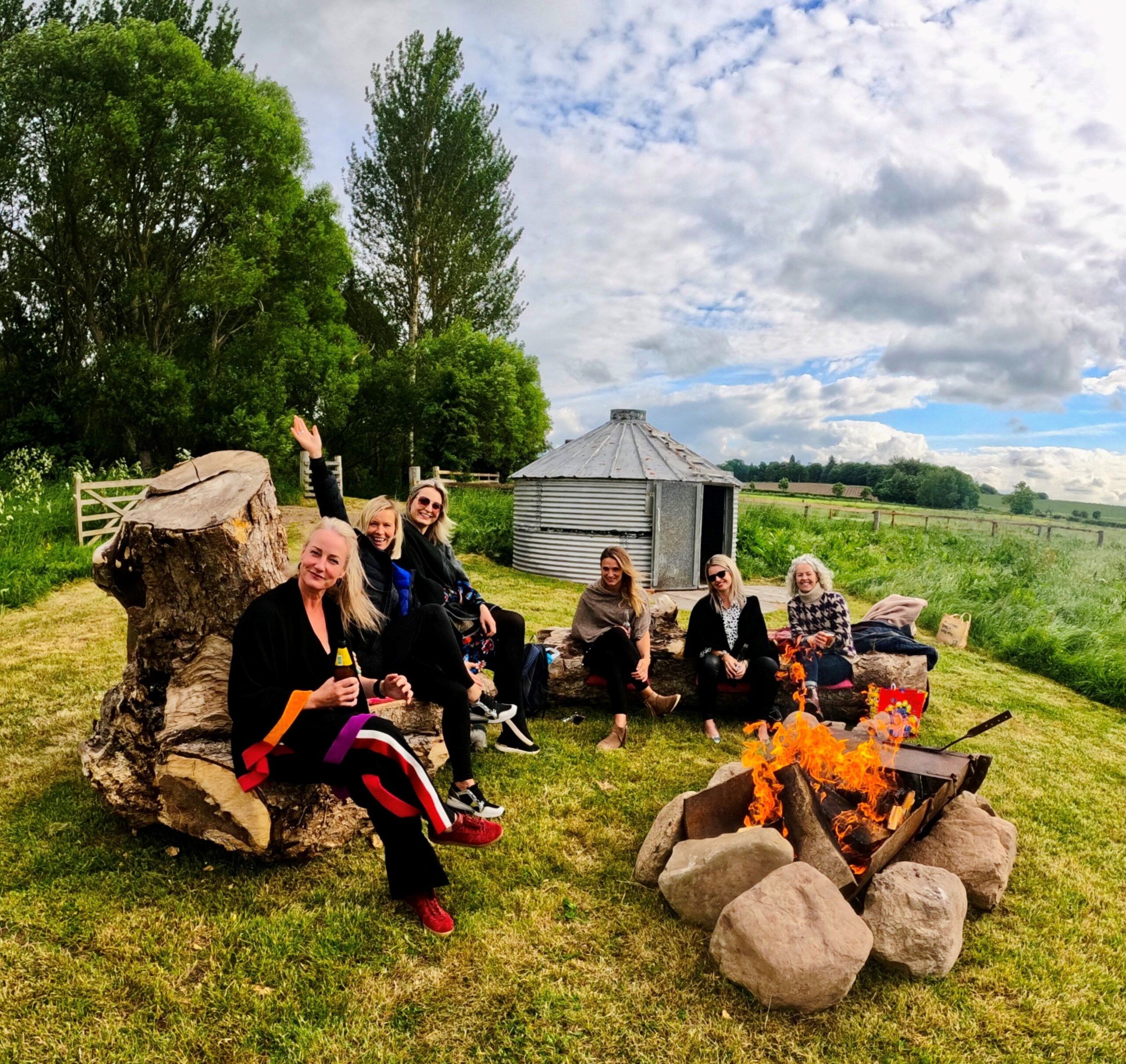A group of smiling people sitting by a campfire