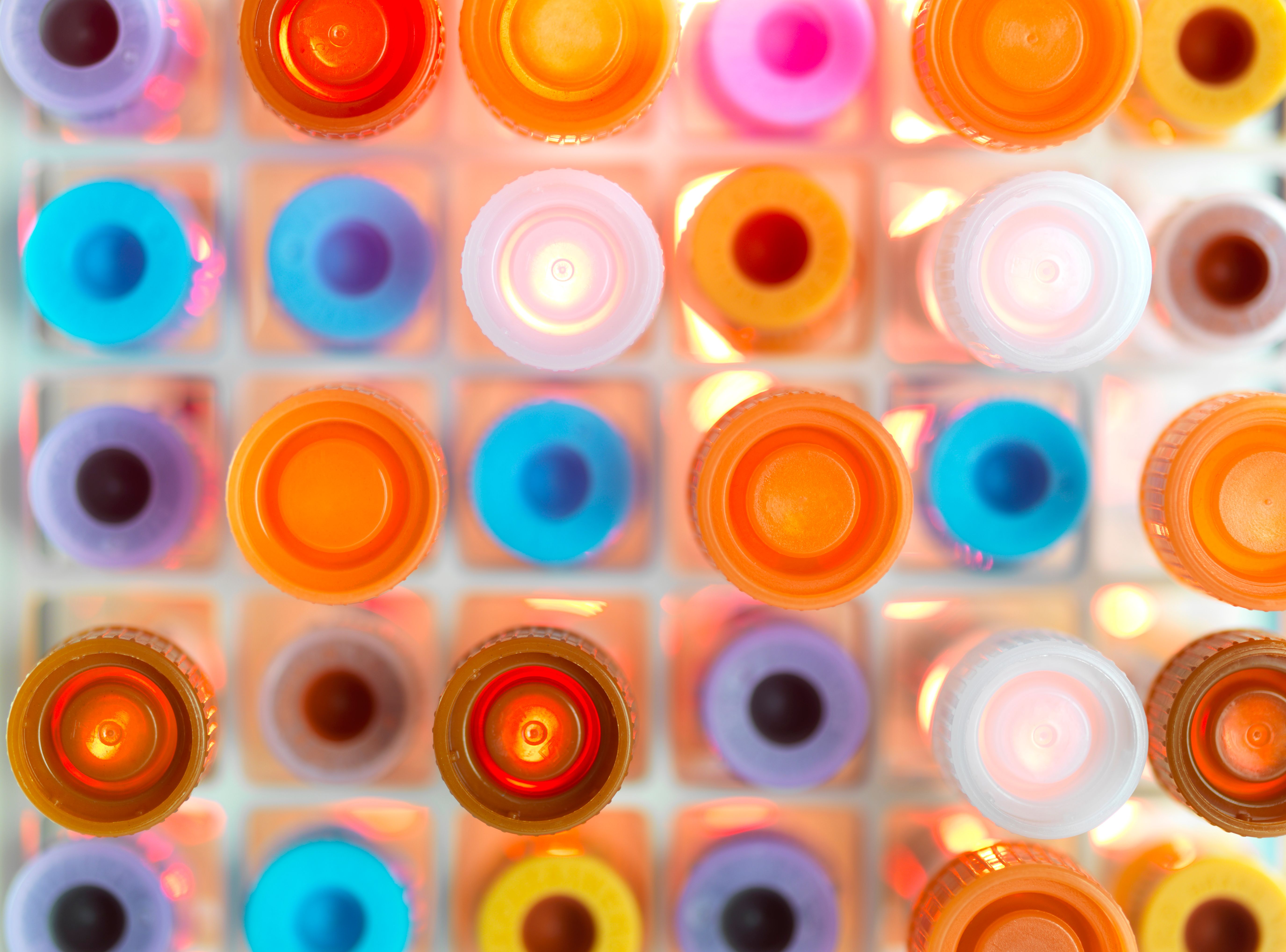 Vibrant, circular laboratory caps in various colors arranged on a white grid.