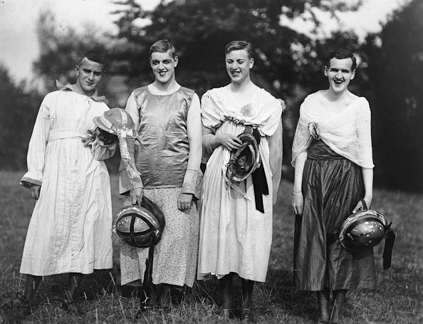 Five young women in vintage attire holding basketballs pose together in a grassy outdoor setting.