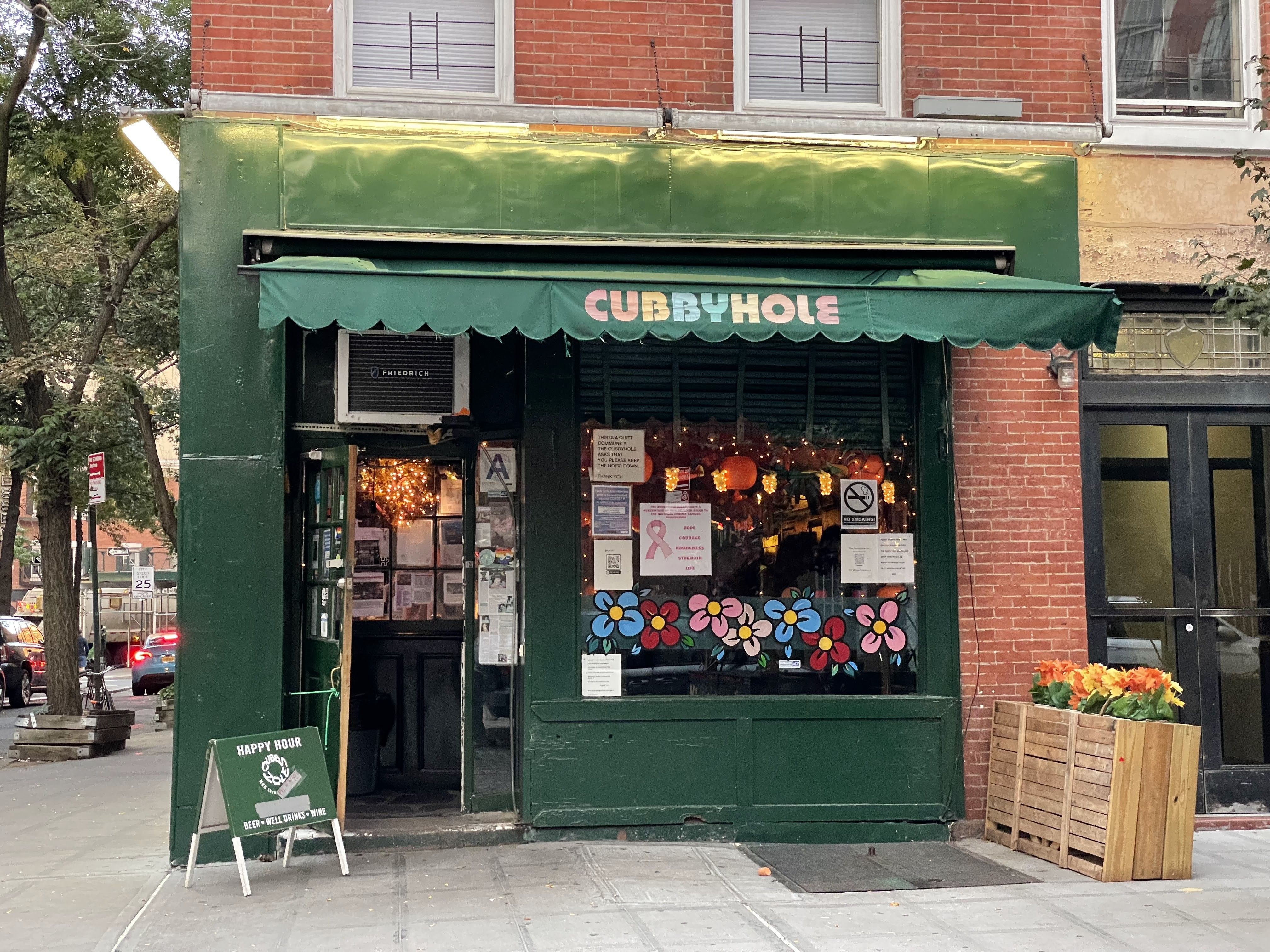 Green storefront with a 'CUBBYHOLE' awning and decorated windows.