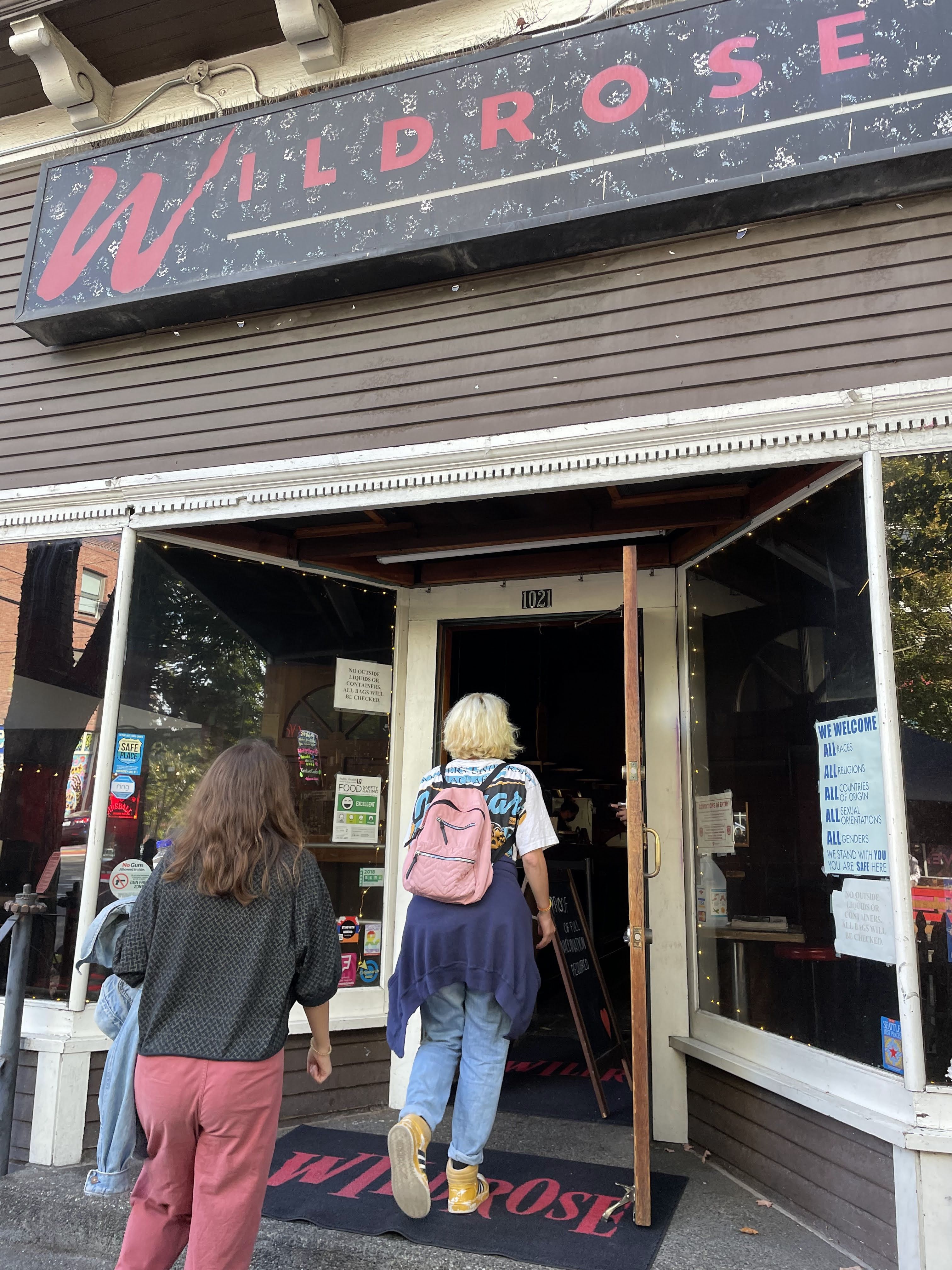Two people entering The Wildrose bar, with its prominent sign above the doorway.